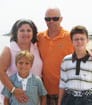 Photo of author SL wearing orange shirt and sunglasses, with his wife and two young sons